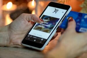 A woman using her smartphone to make a purchase online, holding a credit card in her other hand.