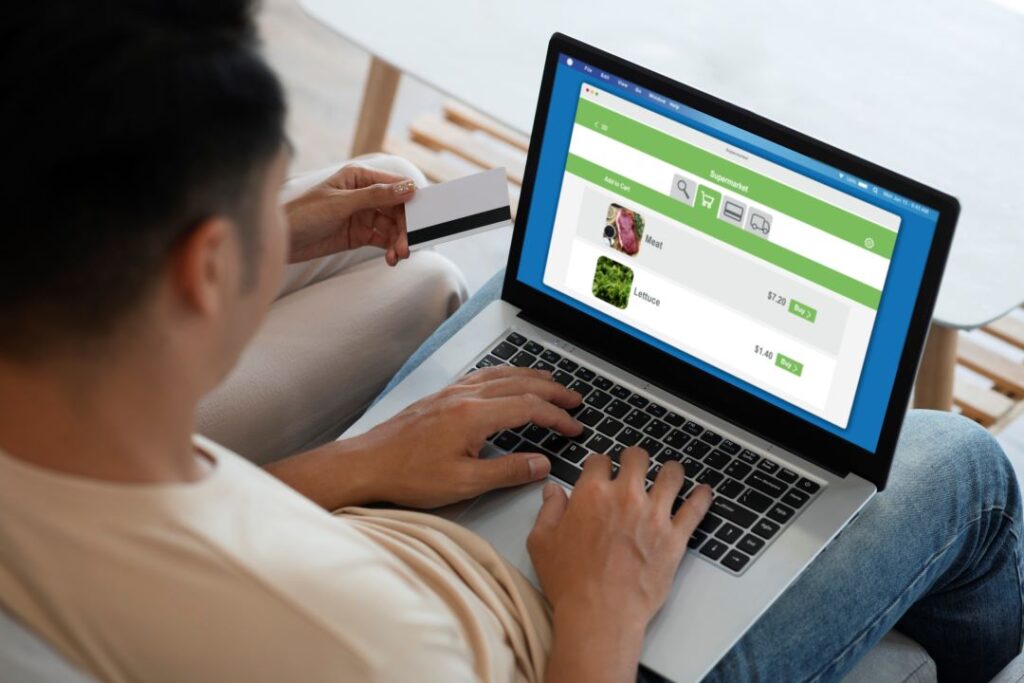 A person using a laptop to shop online, with a credit card visible in the background.