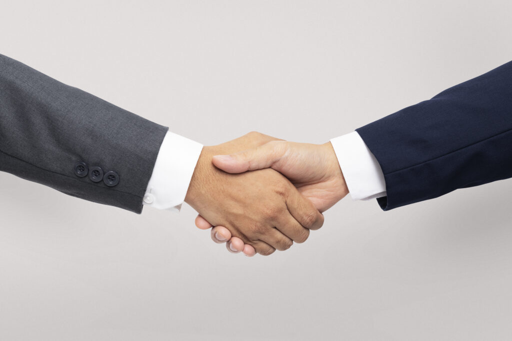 Two people in suits shaking hands to denote the business partnership. Effective Strategies for Performance Marketing,  blog Wonkrew 